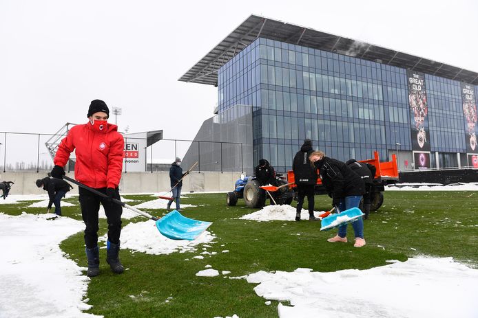 Enkele fans helpen het oefenveld van Antwerp sneeuwvrij te krijgen.