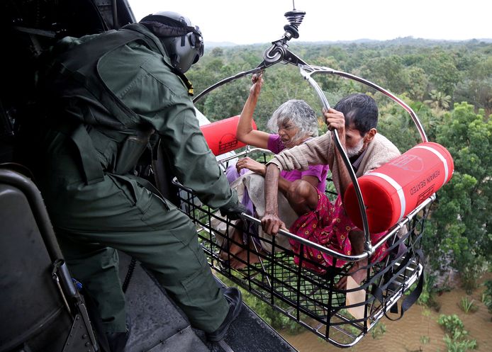 Een man en vrouw worden via helikopter gered uit de overstroomde gebieden.