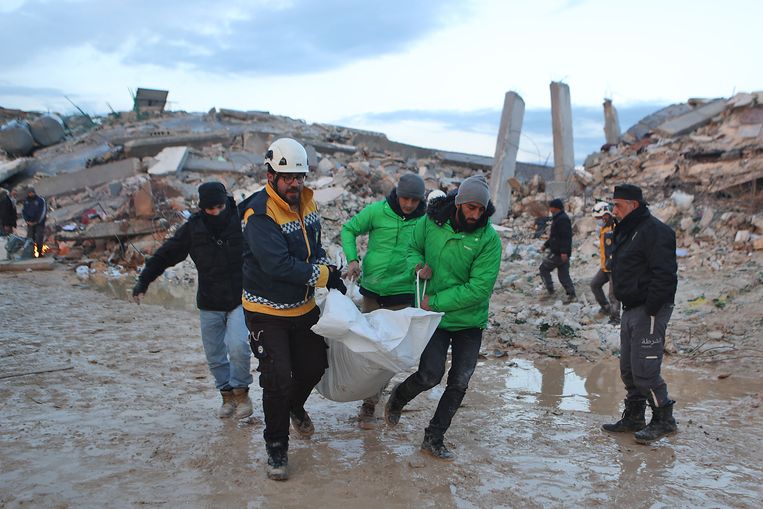 Hulptroepen dragen een lichaam uit het puin in het Syrische Sarmada. De Turks-Syrische grens werd maandag getroffen door een aardbeving van 7,8 op de schaal van Richter. Het dodental in Turkije en Syrië loopt op tot boven de 5000. Beeld AFP