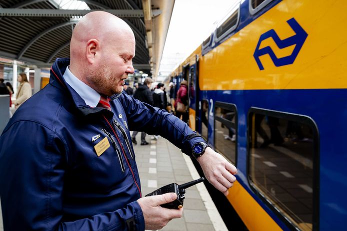 Een conducteur van de NS kijkt wanneer de trein moet vertrekken.