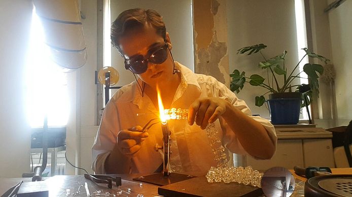 Kunstenaar Jeanine Verloop druk in de weer met het maken van een aandrijfketting van glas.