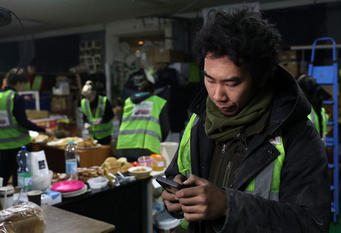Japanse vrijwilliger Takao Tainaka (35) uit Hokkaido kijkt naar zijn telefoon terwijl hij helpt voedselpakketten samen te stellen in Bachmoet, Oekraïne. Beeld van eerder deze maand.