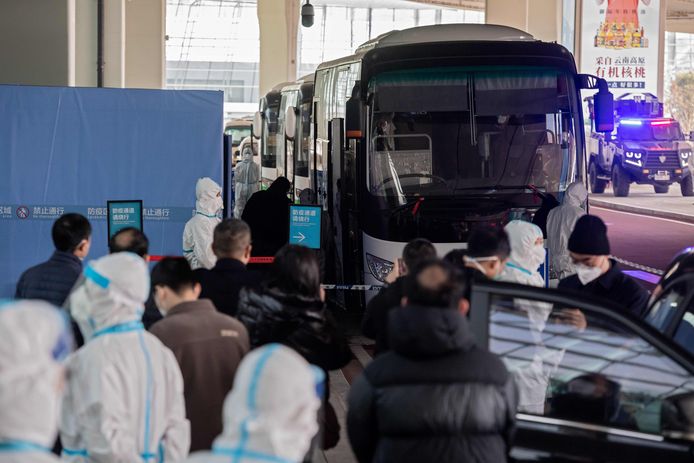 Leden van het WHO-onderzoeksteam stappen aan boord van een bus na hun aankomst donderdag in Wuhan. Ze arriveerden in een apart en afgesloten deel van de luchthaven.
