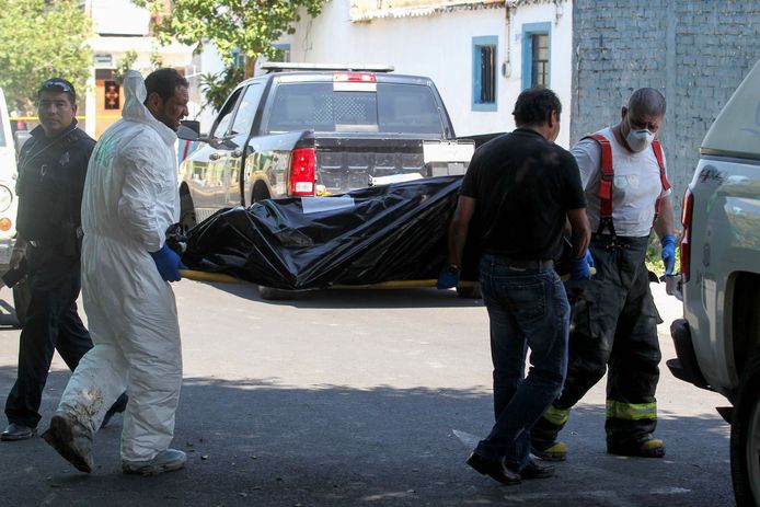 Forensiche onderzoekers dragen een lichaam naar buiten. In een huis in Guadalajara in het westen van Mexico zijn minstens tien verkoolde lijken gevonden.