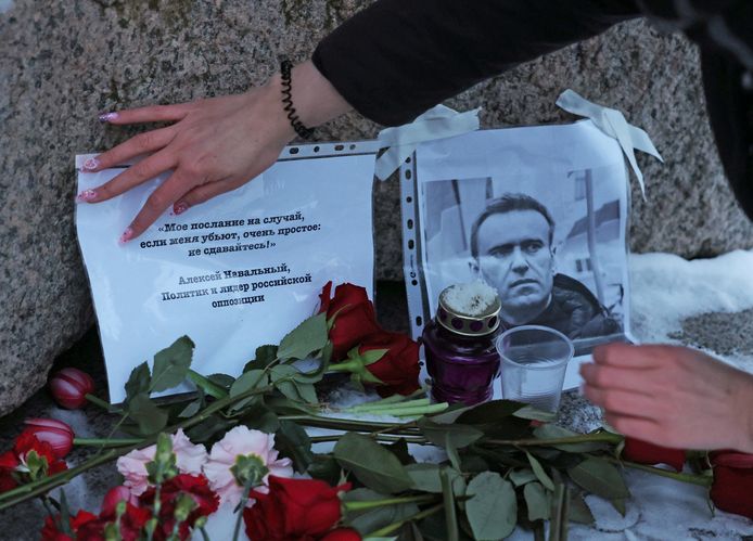 Een vrouw legt bloemen en een boodschap neer aan het monument tegen politieke repressie in Sint-Petersburg.