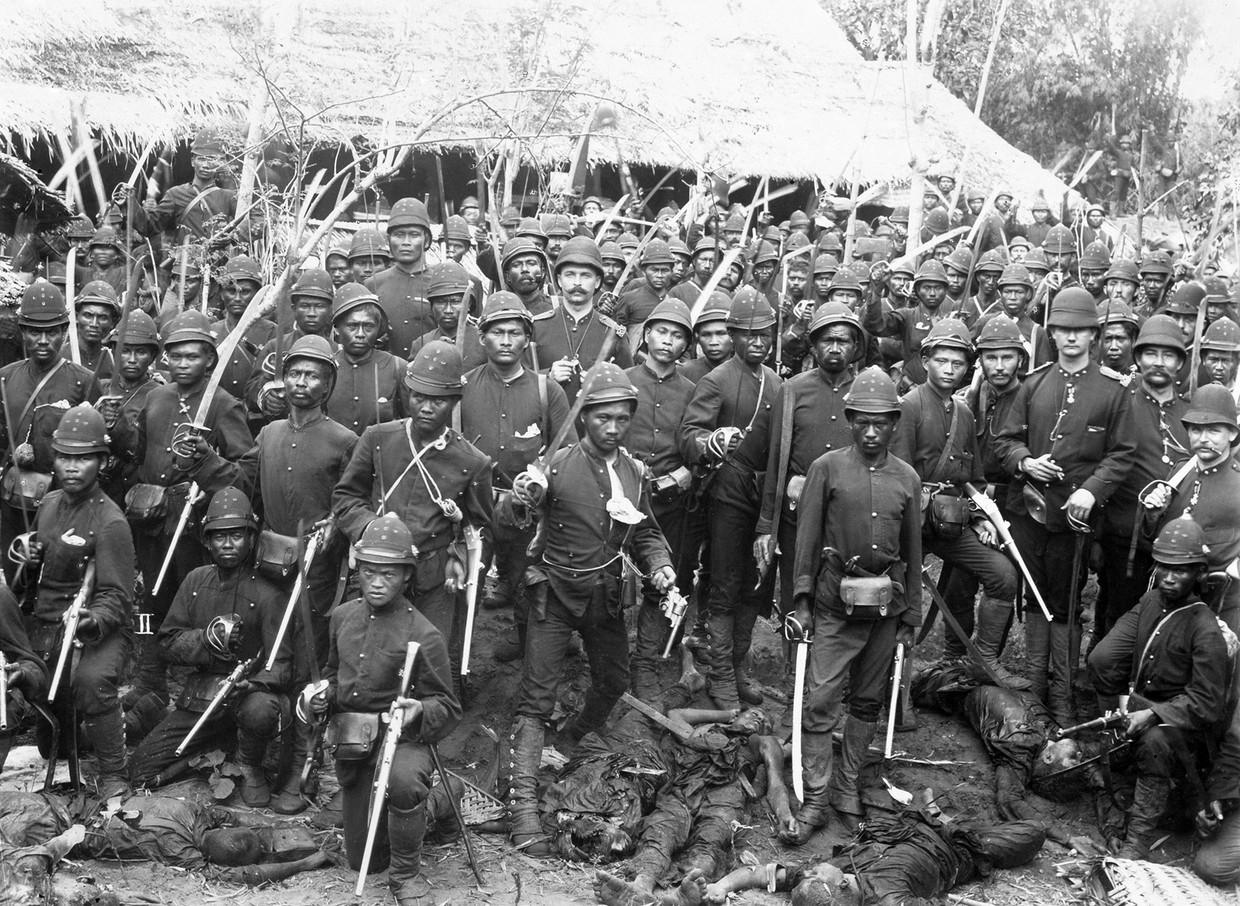 Soldaten van het Nederlandse Korps Marechaussee poseren temidden van lichamen van verslagen Atjehers op het eiland Sumatra, Indonesië, 1898. 