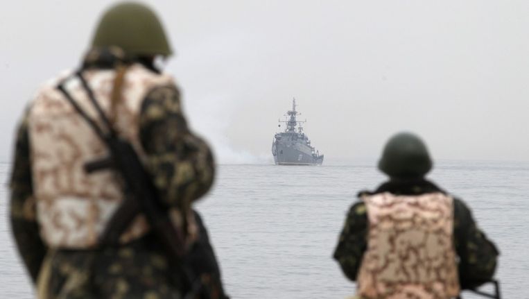 Oekraïnse soldaten kijken naar Russische marineschepen in Sebastopol. Beeld epa