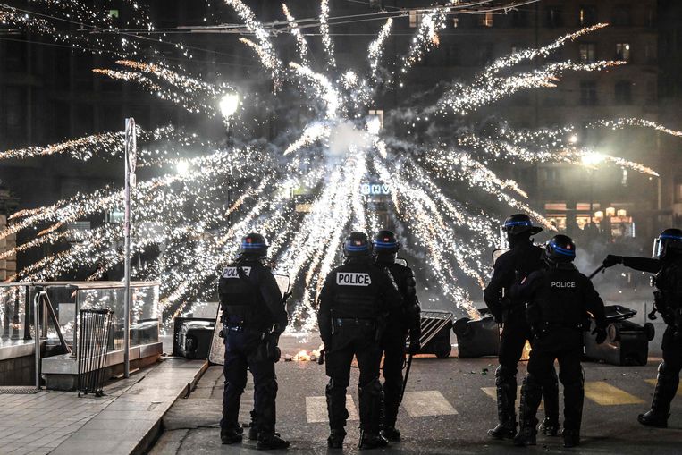 Agenten trotseren vuurwerk dat demonstranten hun kant op gooien tijdens protesten tegen de pensioenhervormingen in Lyon op 16 maart.  Beeld Olivier Chassignole / AFP