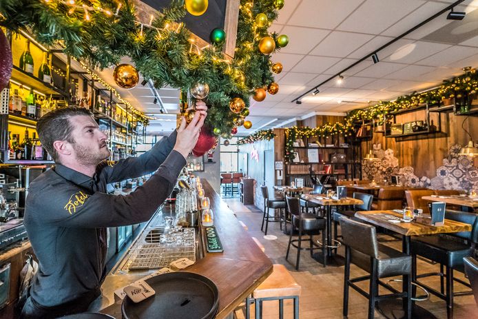 Medewerker Richard Kouwenhoven hangt kerstballen op om de versiering compleet te maken.
