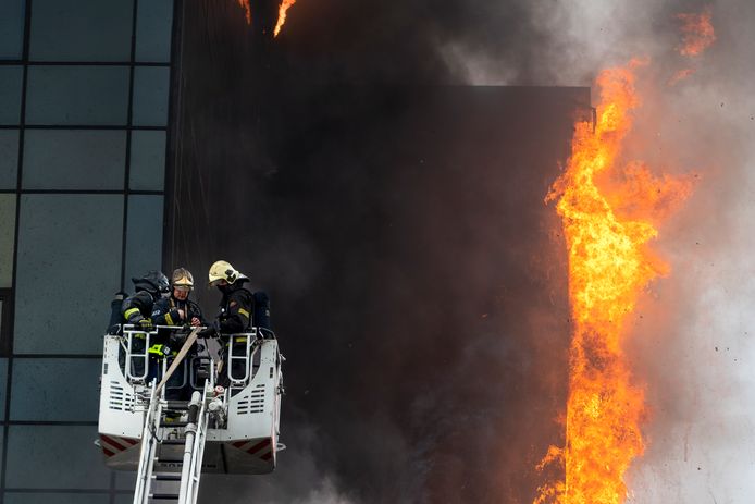 Brandweermannen proberen de brand in het kantoorgebouw te blussen.