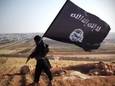 Archiefbeeld van een jihadist met een vlag van IS in het Syrisch-Iraakse oorlogsgebied