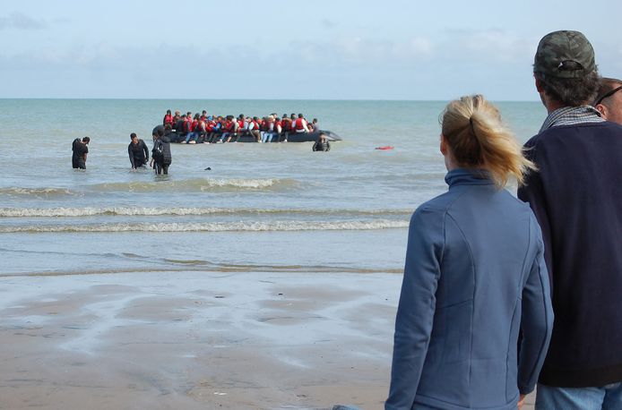 Un canot au large des côtes françaises près de Sangatte le 18 juillet.  Les passagers veulent aller en Angleterre.  Les touristes et les Français regardent depuis la plage.