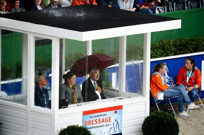 Een jurylid zit donderdag met zijn paraplu in een juryhokje tijdens de Europese kampioenschappen dressuur. Door de harde regen werd de wedstrijd stilgelegd.