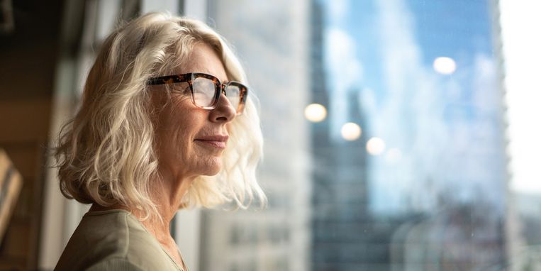 Mature businesswoman looking out of window Beeld Getty Images/iStockphoto
