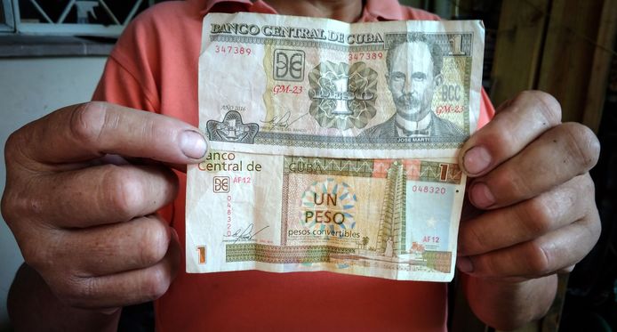 Een man toont een biljet van 1 CUP (Cuban pesos - boven) en 1 CUC (Cuban convertible pesos - beneden).