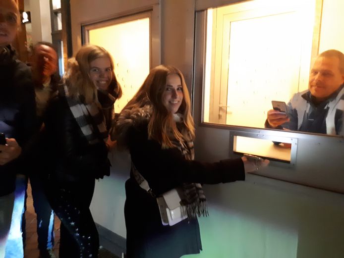 Lisanne Leus (links) en Maartje Engbers halen een coronabandje voordat ze naar de film gaan. In de cabine Dennis Lurink.