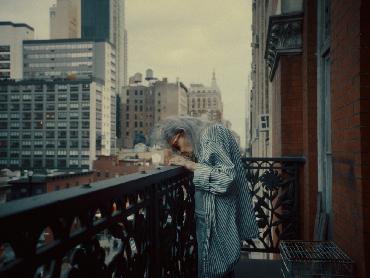 Een van de weinige artiesten die nog overblijven in het Chelsea Hotel kijkt vanop haar balkon naar het New York aan haar voeten. Beeld ©Clindoeilfilms. Photo courtesy of Magnolia Pictures. 
