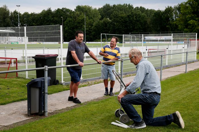 Leden van VV Heukelum plegen onderhoud aan de velden. Achter hen het omstreden pannaveld, dat nu op last van de rechter verwijderd moet worden.