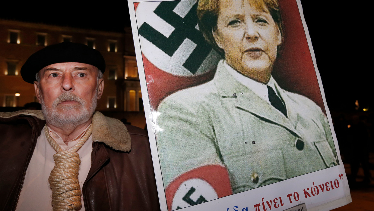 Een man toont een poster van Angela Merkel bij demonstraties voor het Griekse parlement in november vorig jaar. Beeld AP