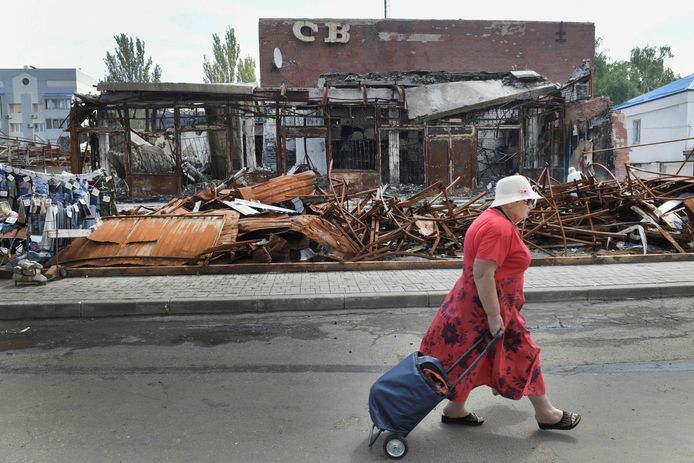 Foto ter illustratie: een vrouw wandelt voorbij een gebombardeerd gebouw in Donetsk, in het oosten van Oekraïne.