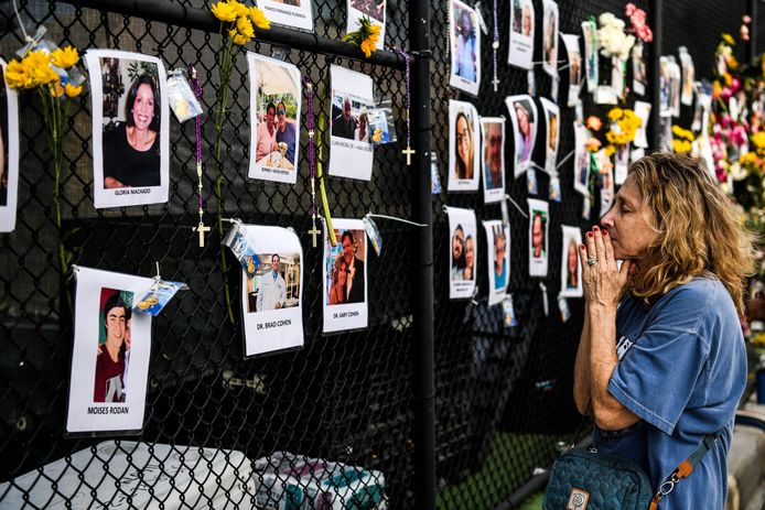 Een vrouw bidt op de plek waar mensen bloemen en kaarten achterlaten voor de slachtoffers.