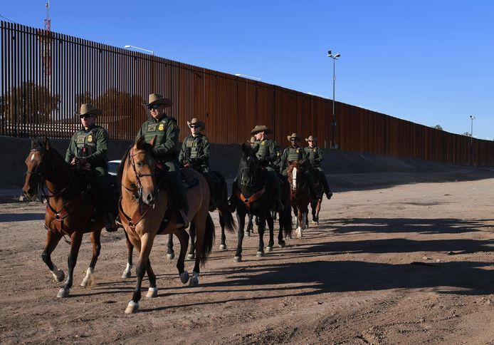 Leden van de  Amerikaanse Border Patrol-politiedienst  patrouilleren te paard aan de grens met Mexico in Calexico (Californië). Een veiligheidshek scheidt de twee landen.