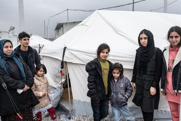 Een Koerdisch-Iraakse familie voor hun tent in het opvangkamp Diavata in Thessaloniki. Beeld Joris van Gennip  