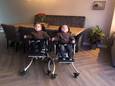 Damin en Ilay zittend in hun speciale rolstoelen, die niet meekunnen in de personenauto van het gezin. (actuele foto)