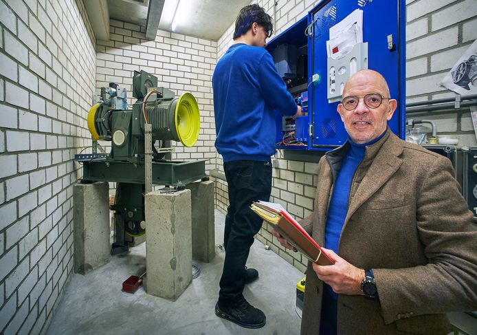 Mario Leijen van Nivå Liften in de machinekamer van de lift in het gemeentehuis in Heesch. Achter hem is Michiel Leijen aan het werk.