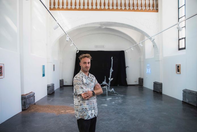 Curator Maxim Renard met links van hem het werk van de Oost-Vlaamse kunstenaar Kris Martin. De kunstenaar strooide 125 kilo bronzen confetti over de vloer.