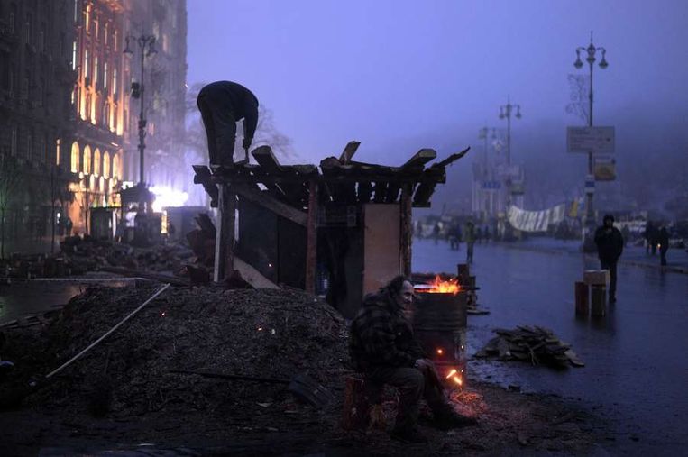 Een zit naast een vuur op het Onafhankelijkheidsplein in Kiev Beeld afp