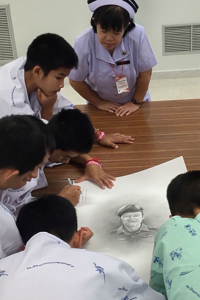 De jongens schrijven kleine boodschapjes naast het portret van de overleden Saman Kunan.