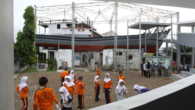 Kinderen in de West-Indonesische provincie Atjeh spelen naast een huis waar een vissersboot op terecht kwam door de verwoestende vloedgolf op 26 december 2004. Beeld AP