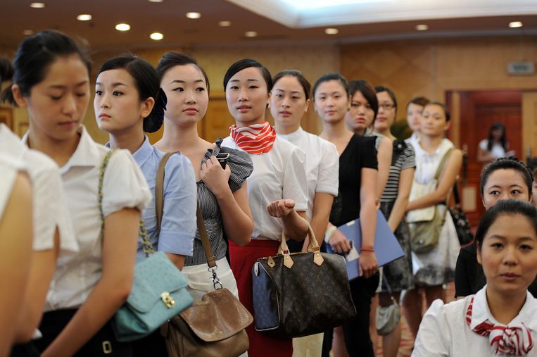Jonge Chinese vrouwen in de rij voor een sollicitatie als stewardess. Beeld AFP
