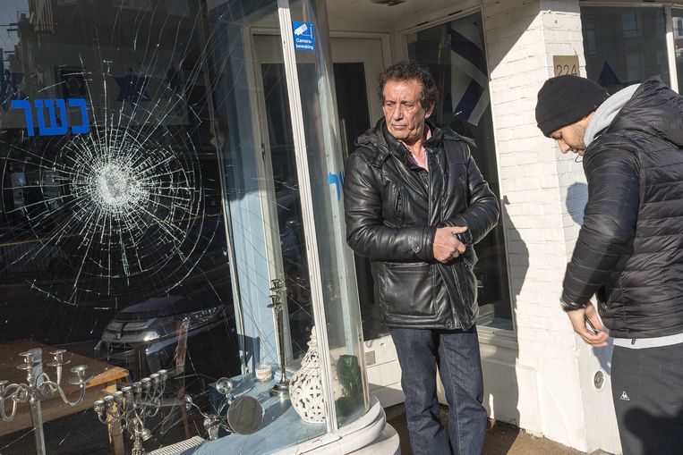 Eigenaar Daniel Baron (R) staat met zijn vader voor het Israëlische restaurant HaCarmel en laat de schade aan zijn restaurant zien, 2 maart.  Beeld ANP