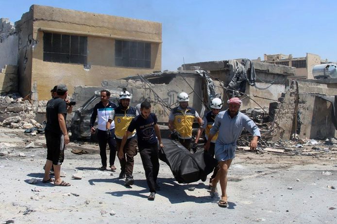 Syrische hulpverleners (met witte helmen) dragen een slachtoffer weg na een luchtaanval op Idlib in juni.