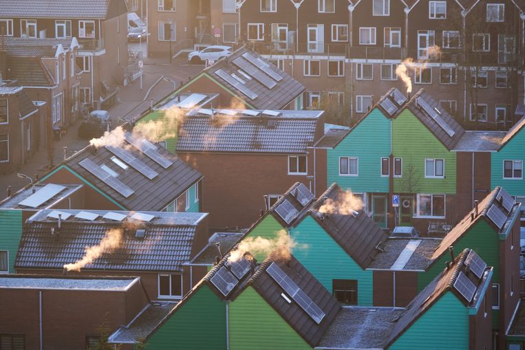 Rook uit enkele schoorstenen in een woonwijk in Zaandam. Op veel daken liggen al zonnepanelen. Beeld ANP / Kim van Dam