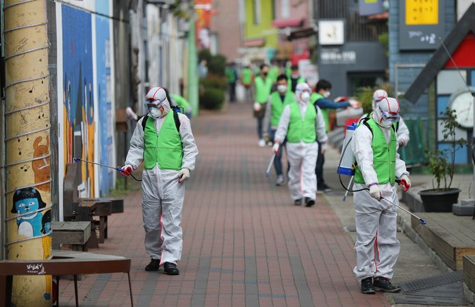 Gezondheidswerkers desinfecteren een straat in Zuid-Korea.