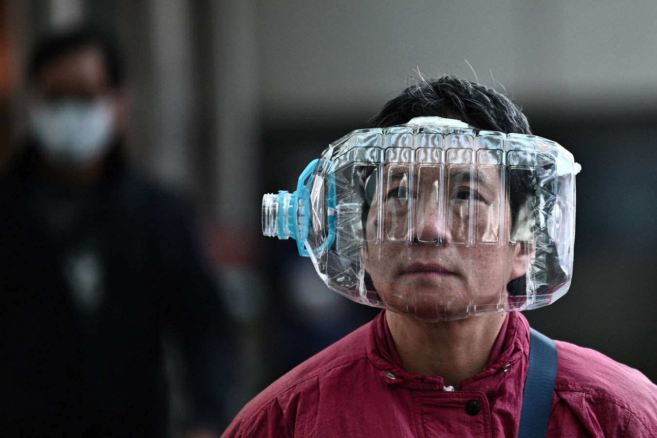 Un habitant de Wuhan avec une bonbonne d'eau vide sur la tête.