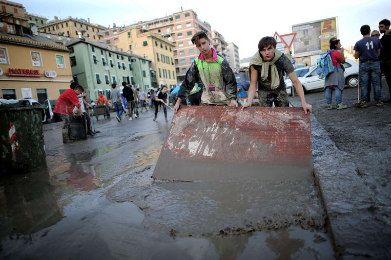 Jongeren in Genua werken vegen modder van de straat. Beeld afp