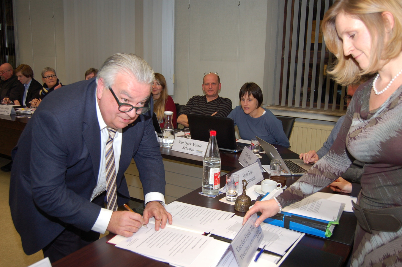 Oswald Vansintejan plaatst nog een handtekening terwijl gemeenteraadsvoorzitter Marleen Van den Eynde toekijkt.