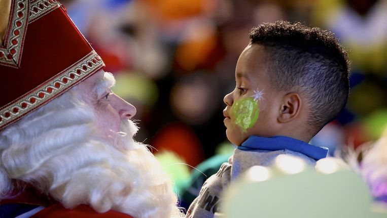 Sinterklaas begroet een kind in het Spoorwegmuseum tijdens een sinterklaasfeest met kinderen uit opvangcentra. Beeld ANP Kippa