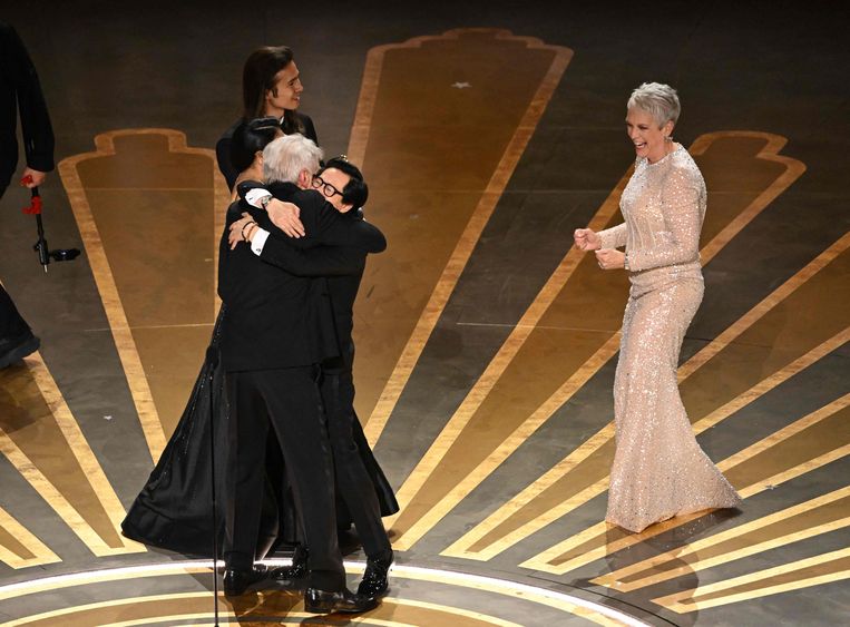 Acteur Ke Huy Quan knuffelt acteur Harrison Ford na de uitreiking van de Oscar voor beste film voor Everything Everywhere All at Once. Actrice Jamie Lee Curtis kijkt toe.  Beeld AFP