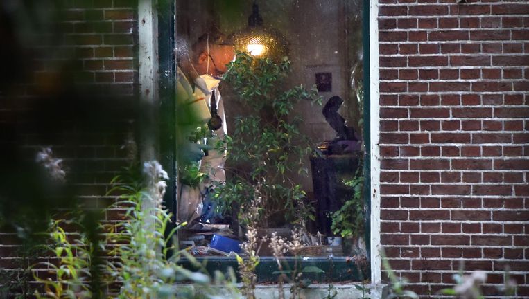 Een forensisch onderzoeker is woensdag op zoek naar sporen in het huis in Katlijk waar een dag daarvoor twee lichamen zijn gevonden. Beeld Marcel van den Bergh / de Volkskrant