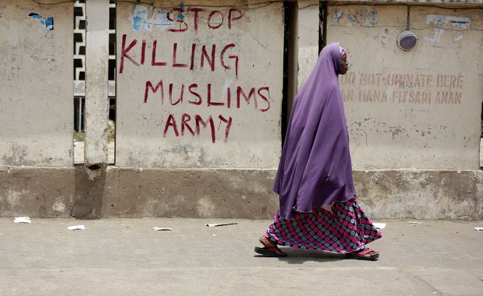 Een moslimvrouw loopt in de Nigeriaanse stad Kano langs een opschrift dat het leger oproept te stoppen met het doden van moslims.