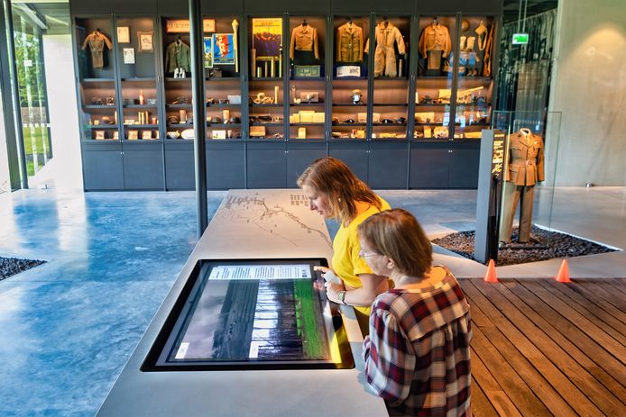 en Wanda Smigielski (voorgrond) en Wendy Dujardin kijken in het Generaal Maczek Memorial naar foto's van toen en nu. In de vitrines is een deel van de collectie van het voormalig museum te zien.