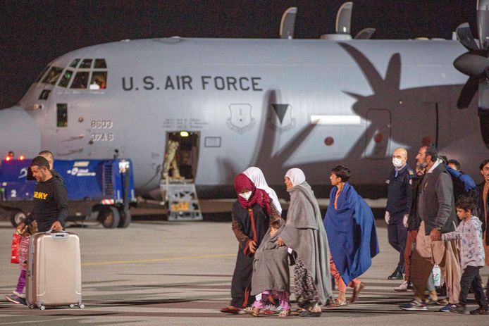Afghaanse families worden op de luchthaven van Kaboel begeleid naar militaire vliegtuigen.