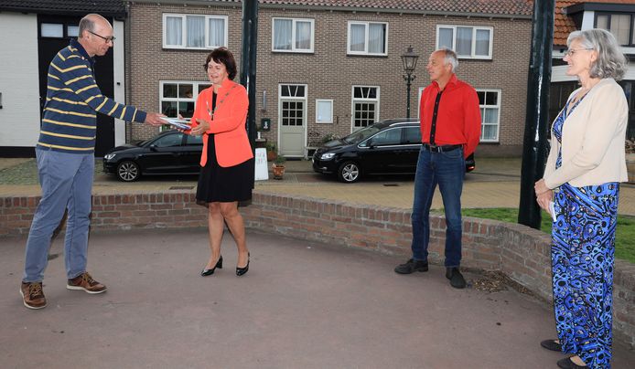Han Almekinders (links) overhandigt het boekje aan burgemeester Marga Vermue, Eric van Rootselaar en Anneriek van Heugten kijken toe.