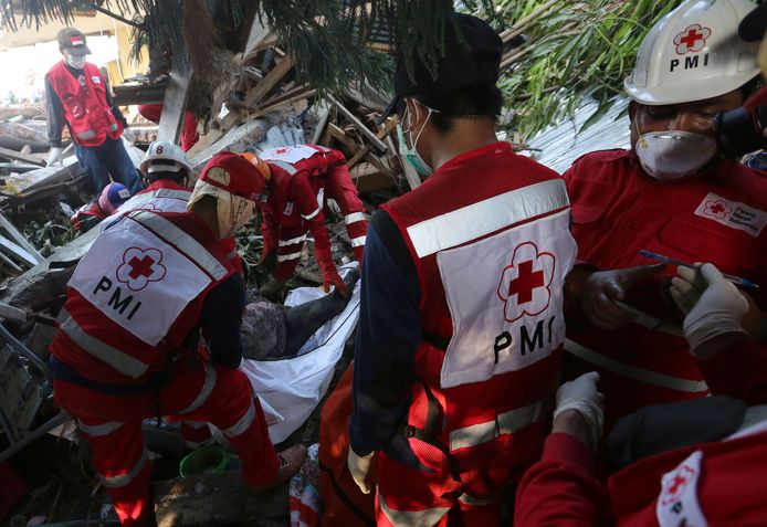 Hulpverleners van het Rode Kruis halen een lichaam van een tsunamislachtoffer uit het puin na de aardbeving en tsunami in Palu op het Indonesische eiland Sulawesi.