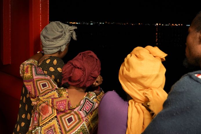 Enkele migranten kijken naar de lampjes op het Italiaanse eiland Lampedusa vanaf de Ocean Viking.  (14/09/2019)